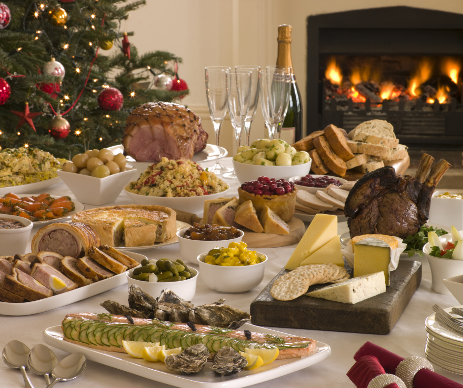 Tempting Christmas buffet of carbs and sugary foods with a fireplace burning brightly in the background and a Christmas tree on the left.